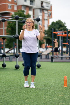 Senior woman exercising outdoors in urban park gym