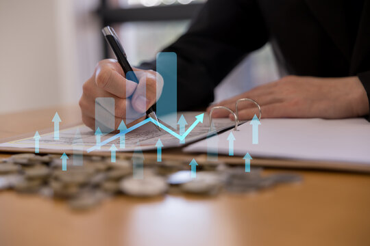 Businessperson using smartphone with magnifying glass over coins, house icon rising arrows, representing real estate investment, property market growth finance mortgage home valuation.