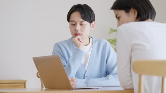 パソコンを見て会話する夫婦・カップル