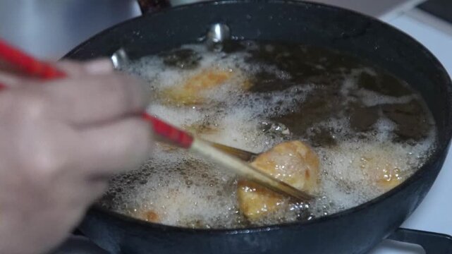 チキンカツを揚げる女性