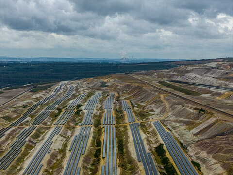 Aerial view of the solar farm on the terraced landscape of the Tagebau Hambach open-pit mine with industrial infrastructure in the background in Elsdorf, Nordrhein-Westfalen, Germany.