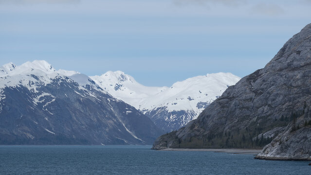 Breathtaking and impressive panoramic scenic view of Glacier Bay Fjord Inside Passage coast with lush mountain vegetation and trees during summer Last Frontier cruise with ice floating on water