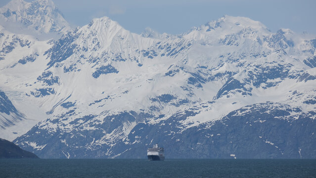 Breathtaking and impressive panoramic scenic view of Glacier Bay Fjord Inside Passage coast with lush mountain vegetation and trees during summer Last Frontier cruise with ice floating on water