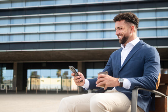 Businessman using smartphone while having coffee outside office