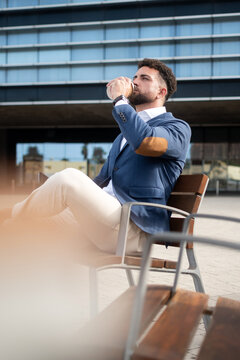 Businessman drinking takeaway coffee outside modern office