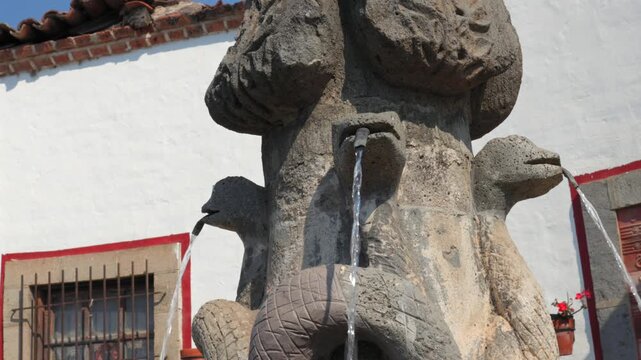 Pila de las Culebras carved stone fountain with flowing water spouts and sculptural reliefs in Tapalpa Pueblo M&aacute;gico, Jalisco, Mexico. Close-up detail shot.