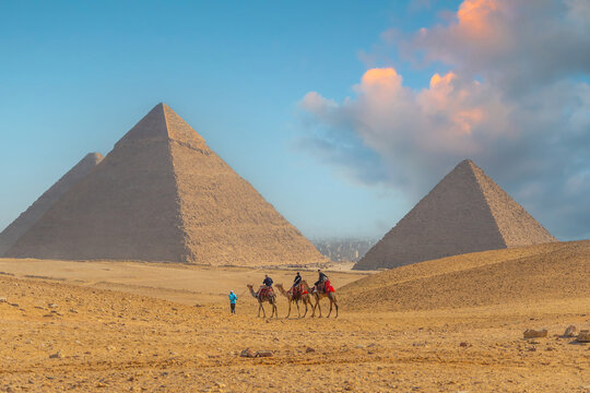 Tourists riding camels in a caravan across the desert sands in Giza