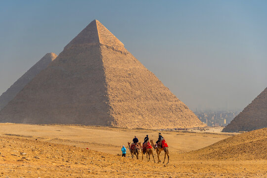 Tourists riding camels in a caravan across the desert sands in Giza