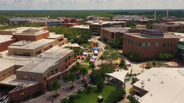 Drone shot of a vibrant student event at UCF in Orlando, capturing colorful tents, courtyards, and modern academic buildings across the busy university campus.