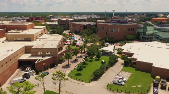 Aerial view of UCF's Memory Mall and Student Union area, bustling with students, vendor tents, and a lively outdoor campus event under sunny Florida skies.