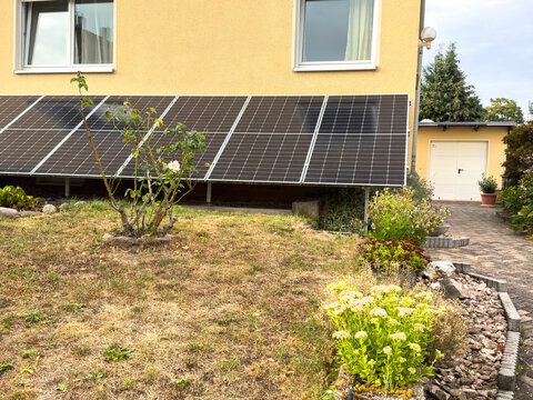 Wall-Mounted Solar Panel in an Urban Garden &ndash; Renewable Energy and Sustainable Home Living