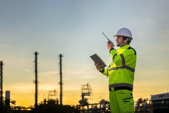 Engineer man in safety gear at oil refinery, Industrial worker with hard hat and radio at oil and gas plant, Construction supervisor in high-visibility jacket at refinery site