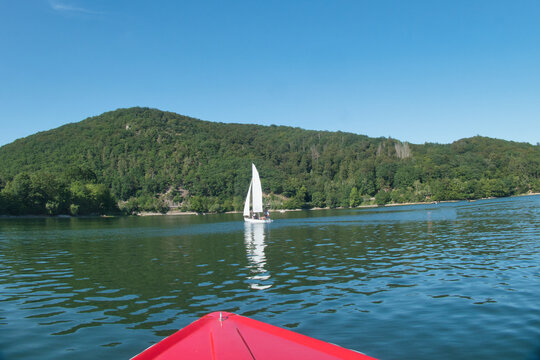 Rotes Boot auf dem Diemelsee mit Segelboot und bewaldeten H&uuml;geln