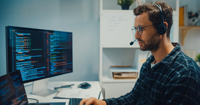 Young Caucasian male technical support specialist wearing headset speaks on computer at office. Professional call center help desk, Cyber security operator service, Online client consultation concept.
