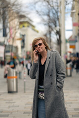 Fototapeta premium Woman talking on phone walking urban street