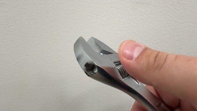 A small adjustable wrench being held in a hand, with the precise moment of adjusting it to fit the correct diameter. The footage captures the twisting motion and the mechanical mechanism