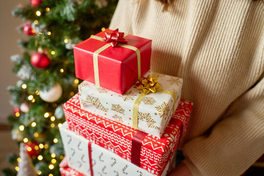 Woman holding stack of wrapped Christmas gifts