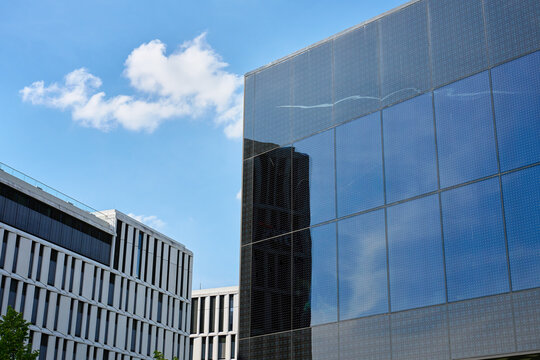 Modern reflective glass building under blue sky with clouds