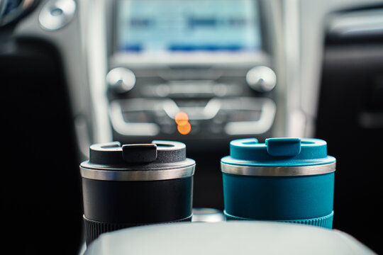 Two reusable coffee cups in car interior