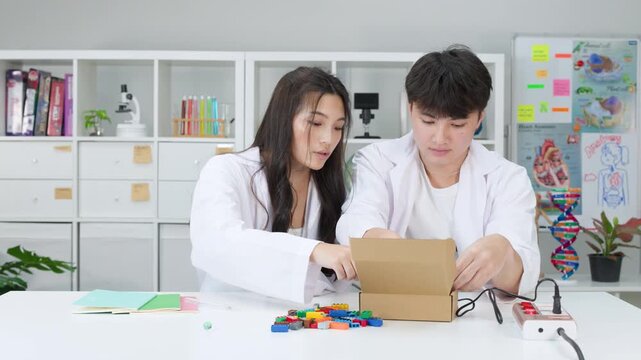 Teenage Students in Lab Coats Conducting Science Experiment with Cardboard Box