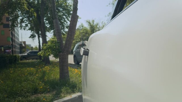 Cropped shot of unrecognizable businessman in suit opening door of electric car and getting inside before vehicle drives off. Perfect for corporate travel and modern executive lifestyle ads