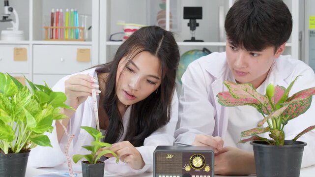Teenage Students in Lab Coats Measuring Potted Plants for Science Experiment