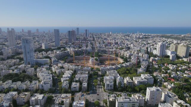 Aerial view of Kikar Hamedina square in Tel Aviv with large scale construction site and urban skyline under clear blue sky.