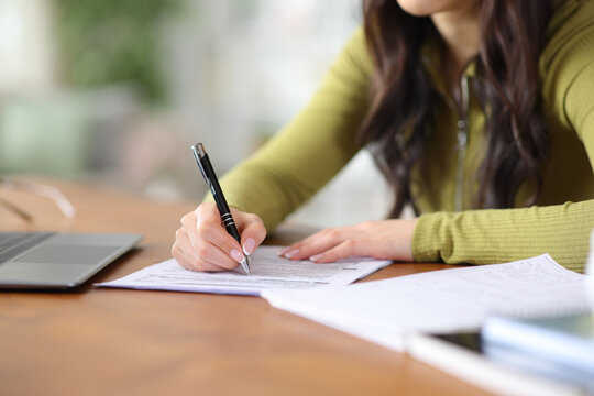 Student hand filling out paper form on a table