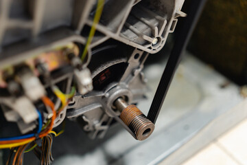 Fototapeta premium Repairing washing machine electric motor and drive belt close up. Appliance maintenance and service concept.