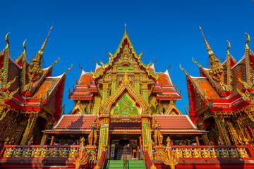 Fototapeta premium Intricate golden architecture of Wat Sri Uthumphon, a famous Buddhist temple in Mueang Nakhon Sawan District, Nakhon Sawan, Thailand, featuring ornate Thai artistic details under a bright clear blue s