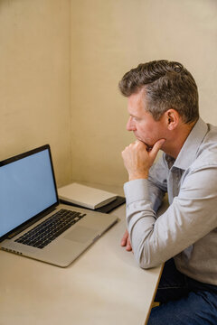 Professional man thinking while working on a laptop in an office