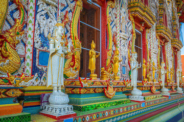 Fototapeta premium Row of white guardian angel statues and golden Buddha figures along the ornate facade at Wat Sri Uthumphon in Mueang Nakhon Sawan District, Nakhon Sawan, Thailand, rich in traditional details.