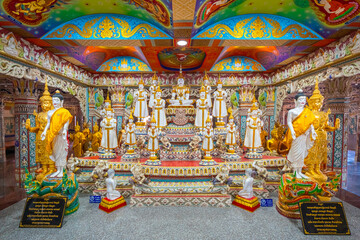 Fototapeta premium White Buddha statues with Thai prayer sign and do not touch warning sign at Wat Sri Uthumphon, Mueang Nakhon Sawan District, Nakhon Sawan, Thailand, set in a colorful decorated hall.