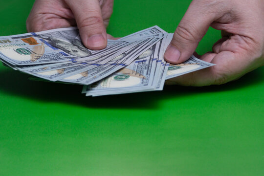 Hands Counting Cash: US Dollar Hundred Bills Money Transaction on Green Background