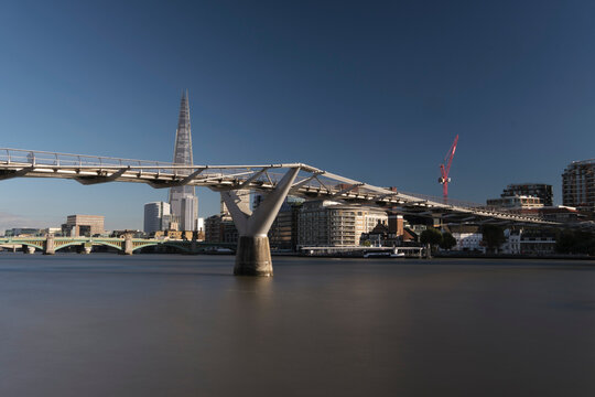 Pedestrians crossing bridge in London with skyscraper.