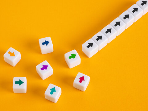 Directional arrow cubes aligning into a straight line on yellow background representing business alignment, team synergy, and strategic vision concept