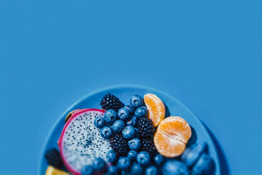 Fresh dragon fruit and mixed berries on a blue plate