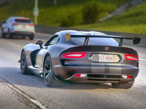 Calgary, Alberta, Canada. August 24, 2026. Low angle three-quarters rear tracking shot of a matte black Dodge Viper ACR driving on a highway.