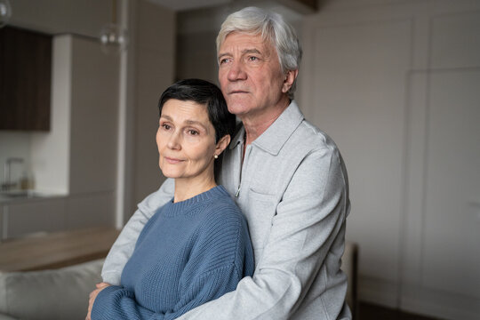Thoughtful elderly man embracing wife warmly. Family happiness, healthy calm relationship, trust and love bond, marital mutual emotional support, senior affection, emotional stability in couple. 