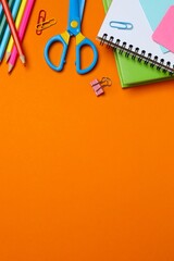 Stationery items with notebook and pencils on orange background, for studying and organizing your workspace © Sunlight