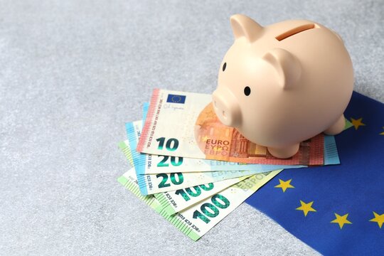 Euro banknotes with piggy bank on the EU flag, close up view