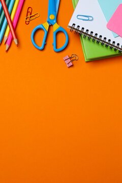 Stationery items with notebook and pencils on orange background, for studying and organizing your workspace