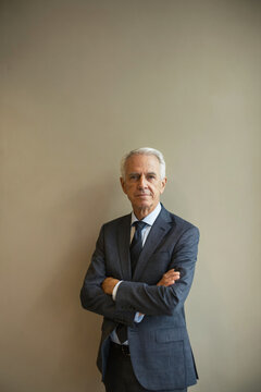 Confident senior executive standing against a neutral wall
