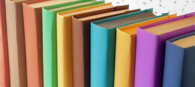 Colorful books with multicolored covers arranged in a row on a table, featuring various complementary color combinations. Books as a symbol of learning and education.