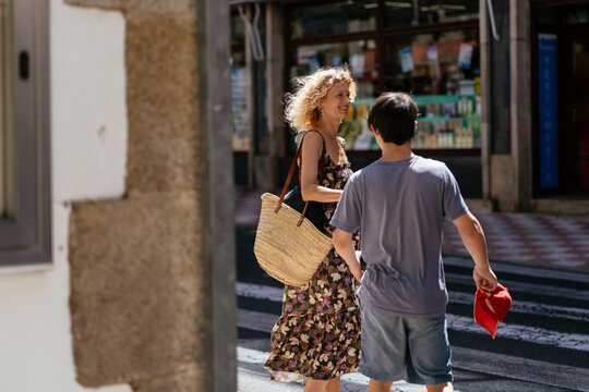 Mother and Teenage Son with Down Syndrome Crossing Street Together During Summer Day in Spain