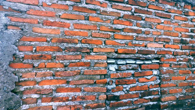 Weathered red brick wall with exposed mortar and a distressed texture.