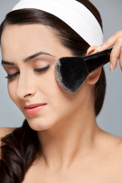 Beautiful woman applying blush