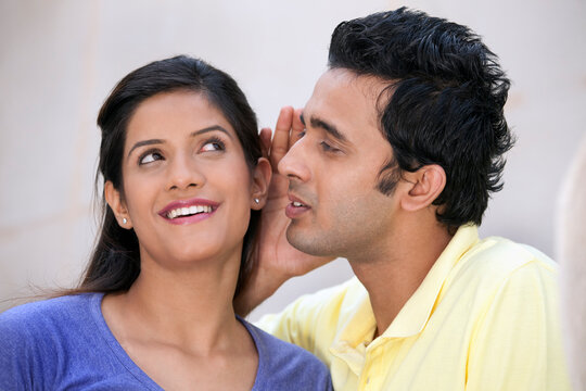 Man whispering in a womans ear