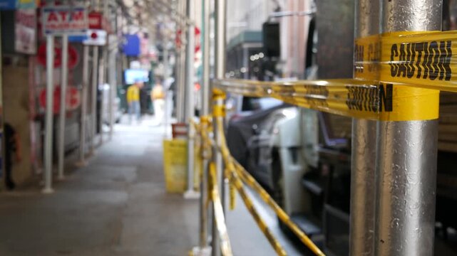 Caution yellow tape and scaffolding on pavement under construction in Manhattan, New York City, United States. Renovation or maintenance, strip barricade or barrier ribbon, scaffold safety warning.