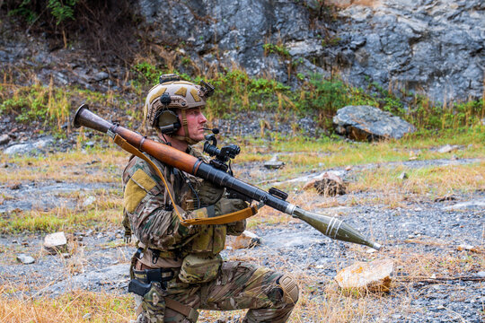 Soldier in military gear prepares for action with a weapon in a rocky training area